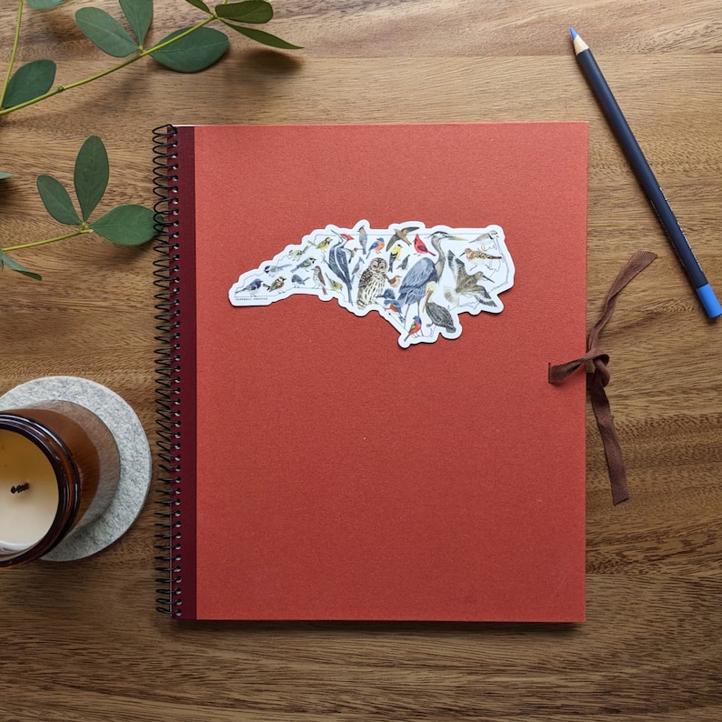 The Birds of North Carolina sticker is shown on a red notebook