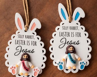 May include: Two Easter ornaments shaped like bunny ears with the text "SILLY RABBIT, EASTER IS FOR Jesus". Each ornament features a Jesus figurine and paw prints. One has pink accents, the other blue.