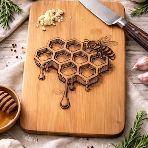 Pode incluir: Tábua de corte retangular de bambu com design de favo de mel e abelha gravados a laser. O favo de mel tem detalhes de mel pingando. Uma faca, alho, alecrim e mel são dispostos ao redor da tábua, sugerindo um tema culinário.
