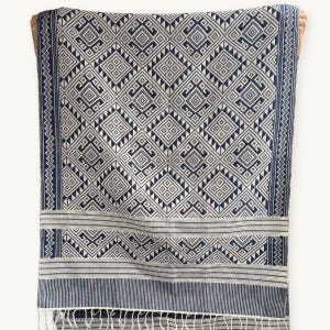 May include: A rectangular textile featuring a repeating navy blue and white geometric diamond pattern. The fabric includes horizontal bands of intricate linear motifs and a decorative border with vertical stripes, finished with a fringe at the bottom edge.