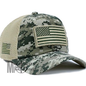 May include: Camouflage baseball cap with a mesh back and an American flag patch. The cap features a digital camo pattern in shades of green, gray, and tan. The American flag patch is in olive green and tan.