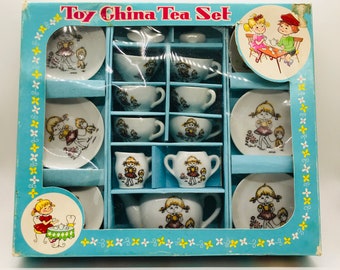 May include: A blue and white cardboard box with a plastic window showing a toy tea set. The set includes cups, saucers, a teapot, and sugar bowl. The box has the words "Toy China Tea Set" printed on the front.