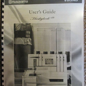 Può includere: Immagine in bianco e nero di una macchina da cucire overlock Husqvarna Viking Huskylock s25. La macchina è su una superficie bianca con uno sfondo bianco. Il testo "Keeping the world sewing" è stampato sotto la macchina.