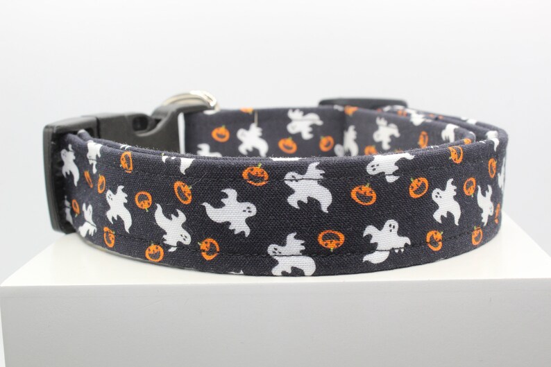 May include: A black dog collar with a white and orange pattern of ghosts and pumpkins.