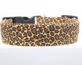 May include: A brown and black leopard print dog collar with a black plastic buckle.