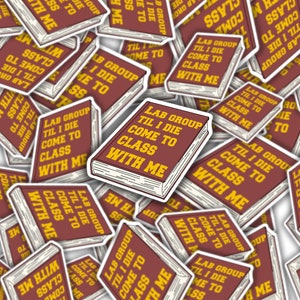 May include: A pile of red and yellow stickers with the text "Lab Group Til I Die Come to Class With Me" printed on them. The stickers are in the shape of a book.