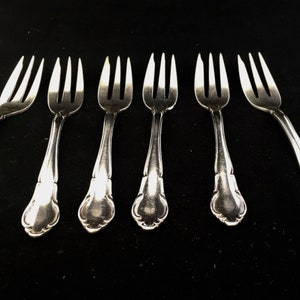 Puede incluir: Seis tenedores de pastel de plata con mangos adornados.