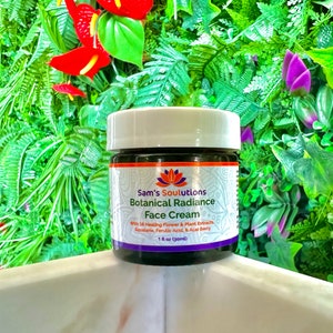 May include: A small glass jar with a white lid containing a dark brown face cream. The jar has a label that reads "Sam's Soulutions Botanical Radiance Face Cream" with the text "With 15 Healing Flower & Plant Extracts Squalane, Ferulic Acid, & Acal Berry 1 fl oz (30ml)".
