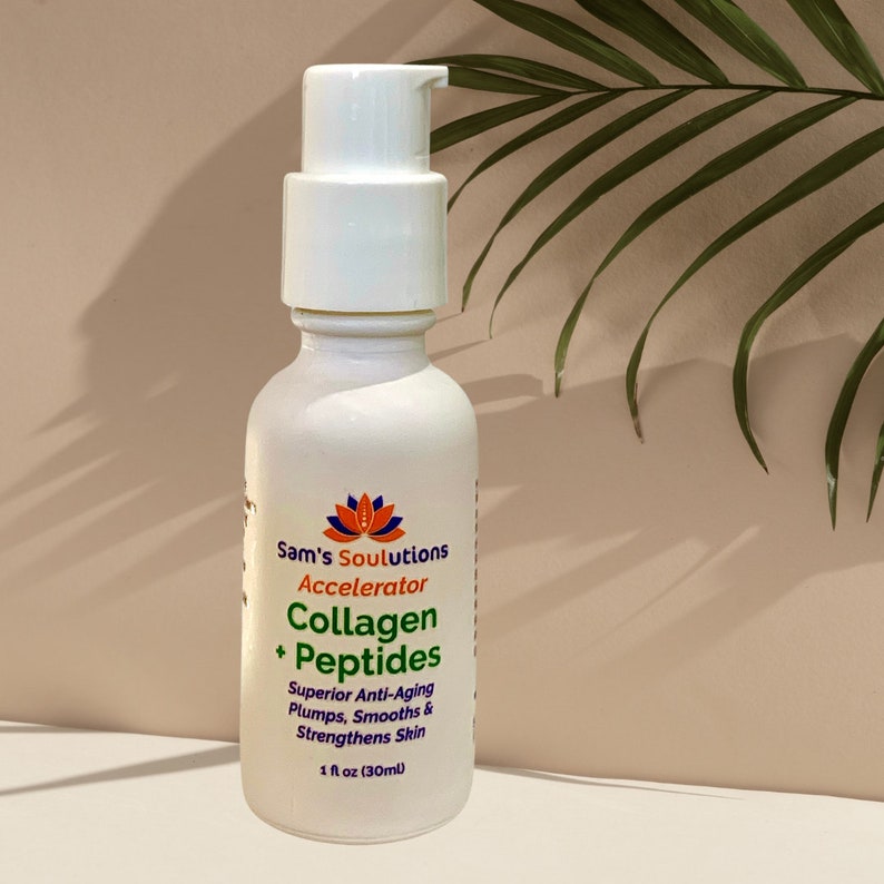 May include: White bottle of Sam's Soulutions Collagen + Peptides Accelerator. The bottle has a pump dispenser and features text including "Superior Anti-Aging" and "1 fl oz (30ml)". The background is a neutral color with a palm leaf.
