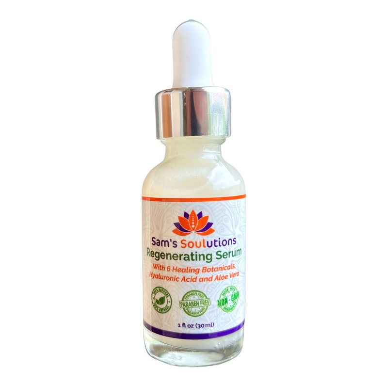Op de afbeelding: Een doorzichtige glazen fles met een zilveren dop en druppelaar, gevuld met een serum. Het etiket is wit met oranje en paarse tekst die "Sam's Soulutions Regenerating Serum" en "With 6 Healing Botanicals, Hyaluronic Acid and Aloe Vera" luidt. Het etiket bevat ook drie ronde logo's: "100% Natural", "Paraben Free" en "Non-GMO". De fles is ge&euml;tiketteerd met "1 fl oz (30ml)".