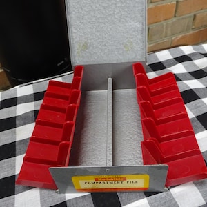 May include: A vintage metal Kodaklide compartment file with red plastic dividers. The file is designed to hold and organize 35mm slides.