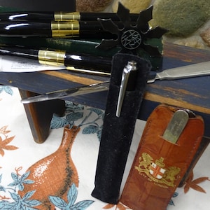 May include: Set of four black and gold pens with a black velvet pen case, a silver letter opener, and a brown leather case with a gold emblem that reads "City of London".