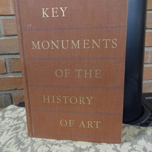 May include: A brown book with gold lettering on the cover. The title is "Key Monuments of the History of Art".