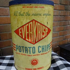 Puede incluir: Lata de patatas fritas Everkrisp vintage. El recipiente cilíndrico tiene un fondo amarillo con letras rojas y azules. El texto dice "Everkrisp Potato Chips" y "Net Weight One Pound".