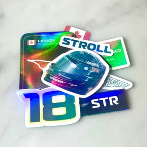 Puede incluir: Un conjunto de pegatinas holográficas con diseños de carreras. Las pegatinas incluyen un casco de carreras, el número "18", el nombre "STROLL" y una bandera canadiense. Las pegatinas tienen un acabado brillante y colores vibrantes.