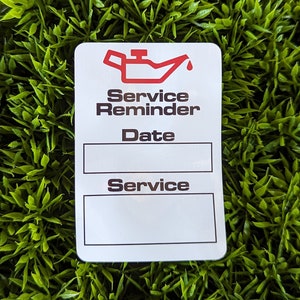 May include: White sticker with a red oil can icon and the text "Service Reminder" with blank spaces for "Date" and "Service".