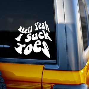May include: A yellow car with a white vinyl sticker on the back window that says "Hell Yeah I Suck Toes".