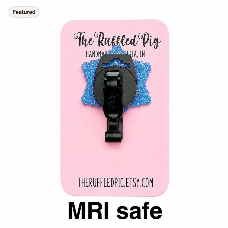 May include: A blue glittery badge reel with a black plastic clip attached to a pink display card. The card features the text The Ruffled Pig HANDMADE IN MUNCIE, IN and THERUFFLEDPIG.ETSY.COM. The badge reel is labeled as MRI safe.
