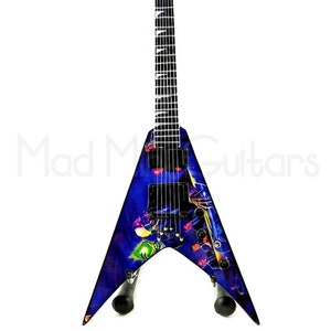 May include: A black electric guitar with a purple and blue finish. The guitar has a unique design with a graphic of a creature with glowing eyes. The guitar is on a stand.