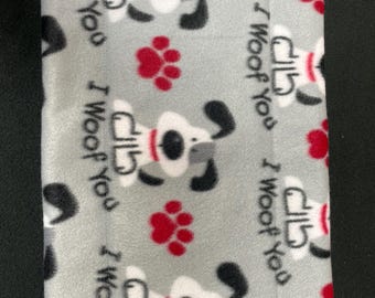 May include: A rectangular gray pet bed with a repeating pattern of cartoon dogs, red paw prints, and the text "I Woof You". The dogs are white with black ears and a red collar.