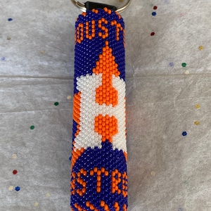 May include: A blue and orange beaded keychain with the word "HOUSTON" and a white letter "H" in the center.