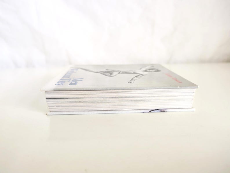 May include: A rectangular book with a light gray cover featuring a black and white illustration of a figure in motion. The title Men Without Ties is printed in blue text on the left side, and the author name is in red text on the right side.