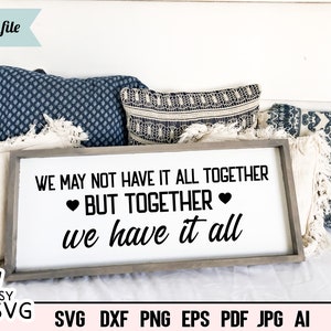 May include: A white wooden sign with black text that reads "We may not have it all together, but together we have it all." The sign has two small black hearts on either side of the word "together".