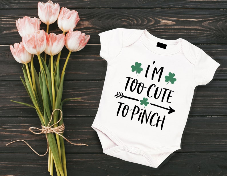 Peut inclure: Combinaison blanche pour b&eacute;b&eacute; avec un motif noir et vert qui dit "I'm Too Cute To Pinch" avec des tr&egrave;fles.