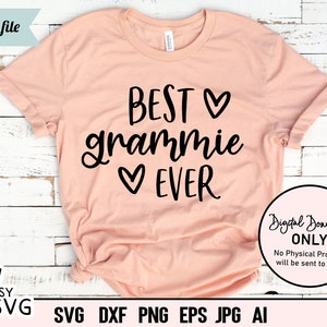 May include: A peach-colored t-shirt with the text "BEST gramme EVER" in black lettering with a heart symbol between the words "BEST" and "gramme" and another heart symbol between the words "gramme" and "EVER".