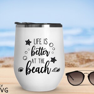 Peut inclure: Un gobelet &agrave; vin isotherme blanc avec un couvercle noir et l'inscription "LIFE IS better AT THE beach" en noir. Le motif comprend des &eacute;toiles de mer, des bulles et des coquillages. Des lunettes de soleil sont &agrave; c&ocirc;t&eacute; du gobelet.