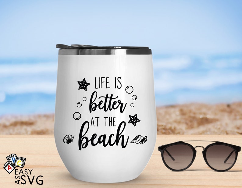 Peut inclure: Un gobelet &agrave; vin isotherme blanc avec un couvercle noir et l'inscription "LIFE IS better AT THE beach" en noir. Le motif comprend des &eacute;toiles de mer, des bulles et des coquillages. Des lunettes de soleil sont &agrave; c&ocirc;t&eacute; du gobelet.