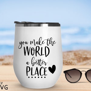 May include: White stainless steel tumbler with a black inscription that reads "you make the world a better place" with a small black heart. The tumbler is sitting on a wooden surface with a pair of sunglasses next to it.