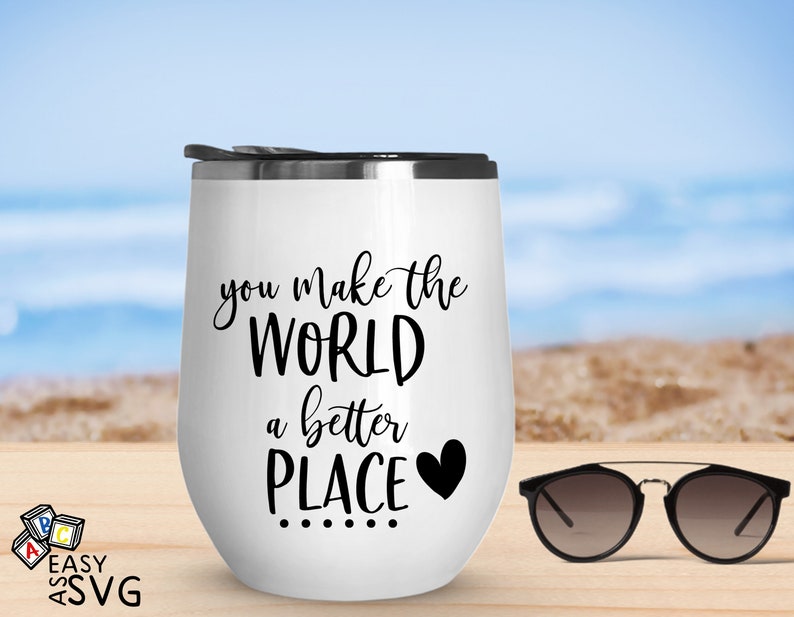 May include: White stainless steel tumbler with a black inscription that reads "you make the world a better place" with a small black heart. The tumbler is sitting on a wooden surface with a pair of sunglasses next to it.