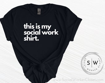 May include: A black t-shirt with the white text "this is my social work shirt." The shirt has rolled-up sleeves and a knot at the bottom. A circular logo with "SW" and "Social Worker Closet" is visible.