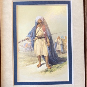 May include: A painting of a man in a blue robe and white turban holding a rifle. He is standing in a desert landscape with other figures in the background.