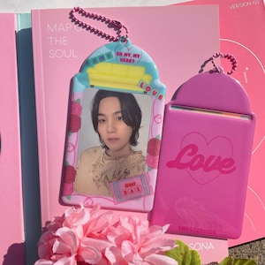 May include: Two pink plastic card holders with a chain. One holder has a photo frame with a picture of a person and the text "Oh My, My Heart" and "Only Bae". The other holder has the word "Love" in pink lettering.
