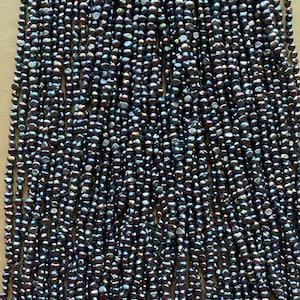 May include: A strand of dark gray freshwater pearls. The pearls are small and round, and they have a slight iridescent sheen.