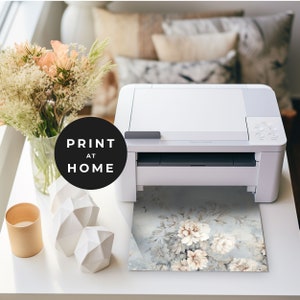 May include: A white printer with a floral print coming out of the paper tray. The print is a light blue background with white and beige flowers. The text "PRINT AT HOME" is on a black circle in the foreground.