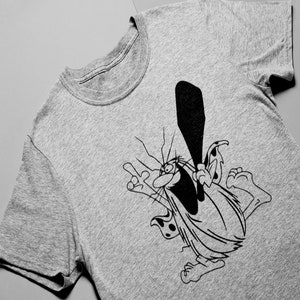 Può includere: Una maglietta grigia con un'illustrazione di cartone animato in bianco e nero di un personaggio con una grande bocca e un bastone.