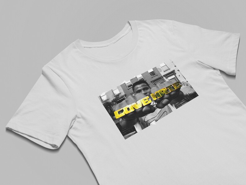 May include: A white t-shirt with a black and white photo of a person holding gold letters that spell "LOVE HATE".