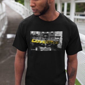 May include: Black t-shirt with a black and white photo of a person holding gold letters that spell "LOVE HATE".