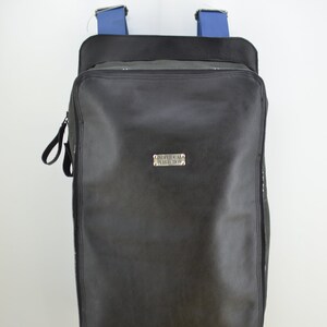 Puede incluir: Mochila de cuero negro con correas azules y una etiqueta de metal plateado que dice "Individual Perfection".