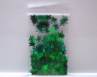 May include: A clear plastic bag filled with green palm tree shaped glitter. The glitter is iridescent and has a holographic finish.
