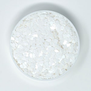 May include: A white bowl filled with white iridescent glitter in the shape of small clouds.