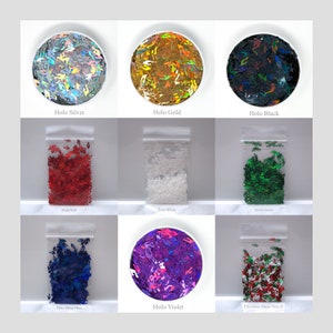 May include: Assortment of holographic glitter in various colors, including silver, gold, black, red, white, green, blue, violet, and a Christmas music note design. The glitter is displayed in small clear plastic bags and bowls.