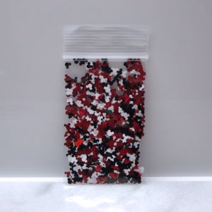 May include: A clear plastic bag filled with red, white, and black glitter shaped like Mickey Mouse heads.