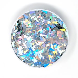 May include: A white bowl filled with iridescent holographic glitter in the shape of small leaves.