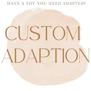 May include: The image features the words "CUSTOM ADAPTION" in a brown serif font, set against a soft, peach-colored watercolor-style background. Above the main text, the phrase "HAVE A TOY YOU NEED ADAPTED?" is written in a smaller, brown font.