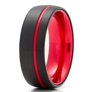 May include: A black tungsten carbide ring with a red inner band and a red line around the outer edge.