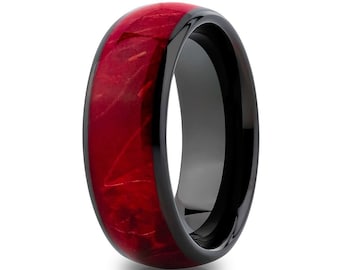 May include: A black tungsten carbide ring with a red wood inlay. The ring has a polished finish and a beveled edge.